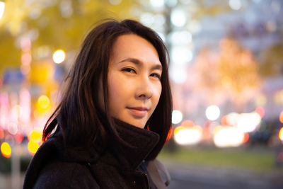 Portrait of smiling woman in city at night