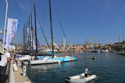 Sailboats moored in harbor by city against sky