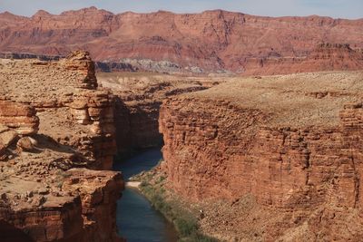 Landscape of steep cliffs and the colorado river between with pink mountains in the background