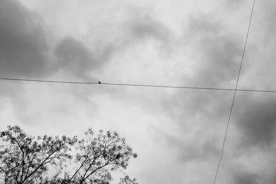Low angle view of power lines against cloudy sky