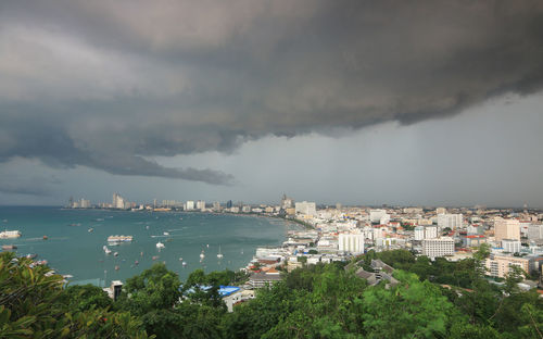 Aerial view of townscape by sea against storm clouds