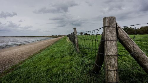 Wooden fence on field against sky