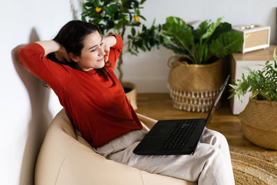 Young woman using laptop while sitting on sofa at home