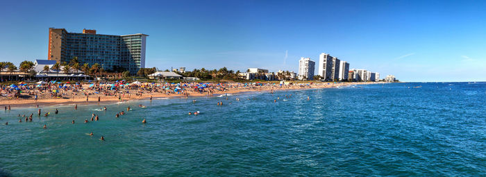 Skyline of crowded sands of deerfield beach near the pier with unrecognizable faces in deerfield