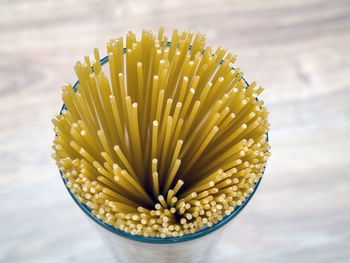 Uncooked spaghetti in glass vase on a wooden background. close-up.