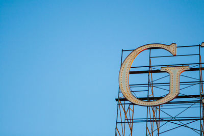 Low angle view of rollercoaster against clear blue sky