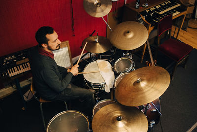 Mature man playing drum set while practicing at recording studio