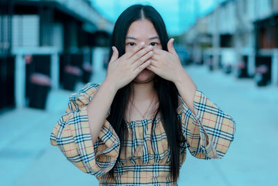 Girl closed her mouth with crossed palms with worried expression.