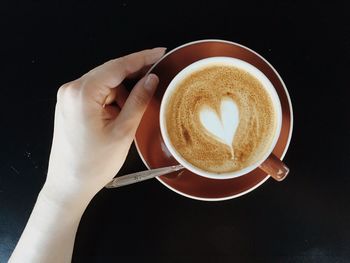 Cropped image of woman with cappuccino served on table