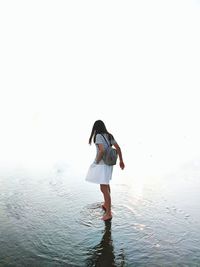 Rear view of woman standing in sea against sky