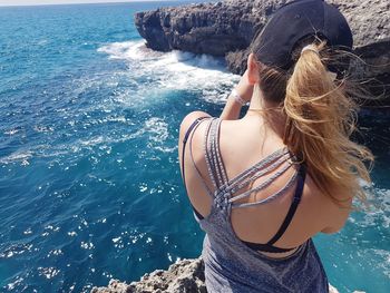 High angle view of woman standing on rock against sea during sunny day