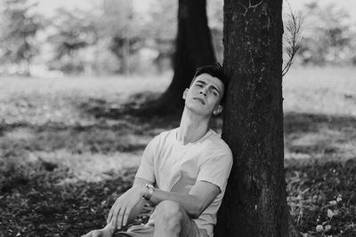 Young woman sitting on tree trunk in forest