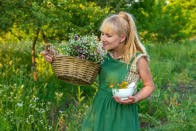 Side view of young woman standing against plants