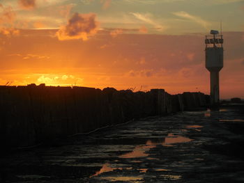 Lighthouse amidst buildings against sky during sunset