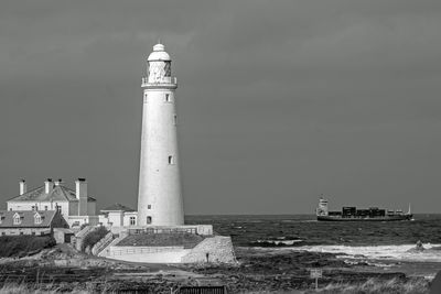 Lighthouse by sea against sky