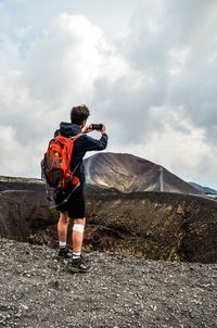 Rear view of man cycling on mountain against sky