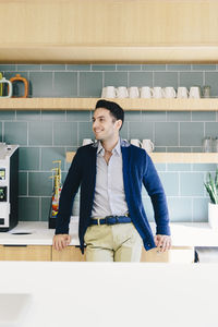 Businessman looking away while standing by kitchen counter in cafeteria at creative office