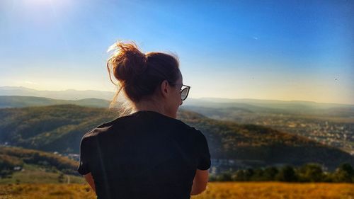 Rear view of woman looking at mountains against sky