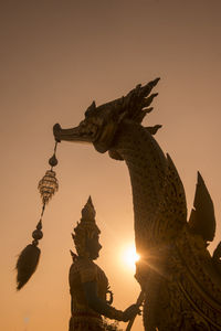 Low angle view of statue against sky at sunset