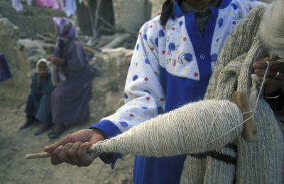 Midsection of girl holding thread holder and woolen material