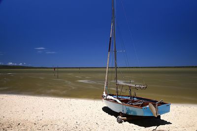 Sailboat moored on sea against clear blue sky