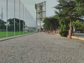 Footpath amidst trees and buildings against sky