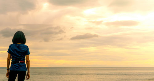 Asian woman watching sunrise sky at sea beach. runner relax after running at tropical beach.