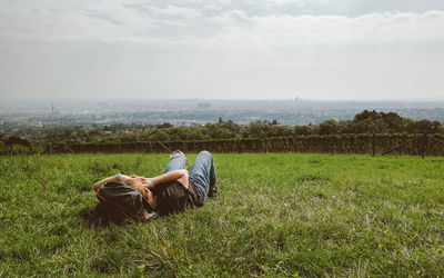 Man lying down on land against sky