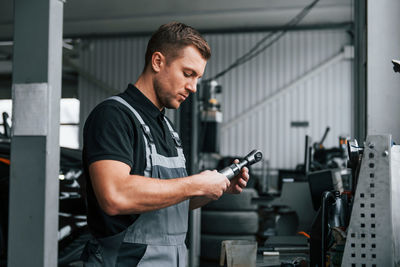 Holding tool. man in uniform is working in the auto service.