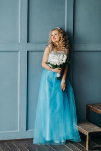 Midsection of woman wearing blue dress holding bouquet