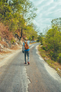 Rear view of man walking on road