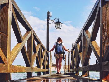 Full length of girl standing on bridge against sky