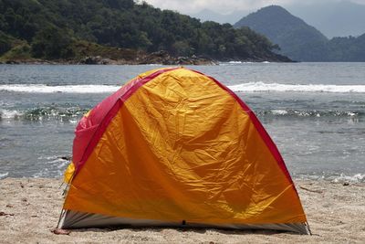 Tent on beach by sea against mountain