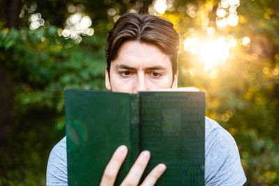 Man reading book against trees