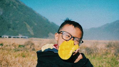 Portrait of child wearing mask on field against sky