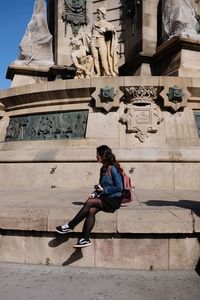 Man sitting on statue against historic building