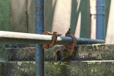 Close-up of rusty metal gate against wall