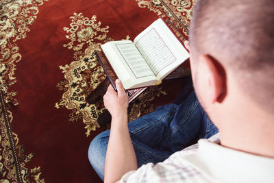 High angle view of man reading koran in mosque