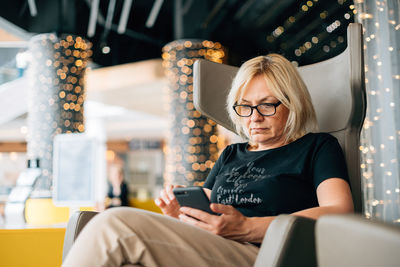 Senior woman using smart phone sitting on chair