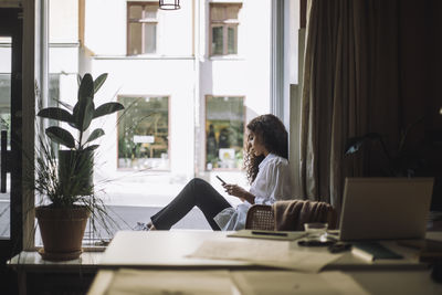 Side view of woman using laptop on table