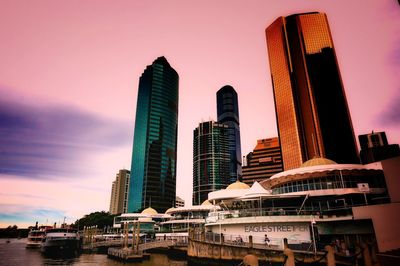 Modern buildings in city against sky during sunset