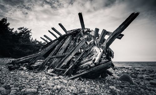 Ship wreck on shore against cloudy sky