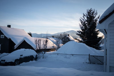 Snow covered houses of picturesque norwegian village with mountain in background.