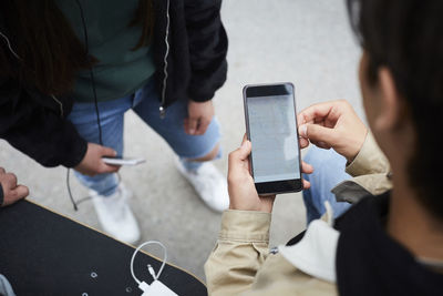 High angle view of man checking map on smart phone while standing with friends