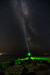 Light trails over sea against sky at night