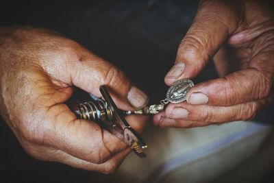 Close-up of hands holding pendant and multi purpose tool