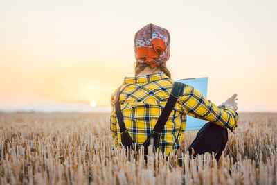 Farmer woman on wheat field doing admin regarding the past harvest