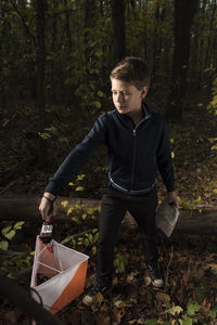 Boy holding basket while standing in forest