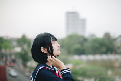 Portrait of woman in city against sky