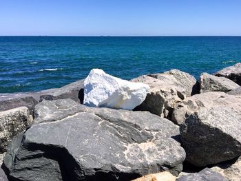 Scenic view of sea with rocky shore against clear sky